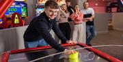 Group of friends playing air hockey at Richardson's Family Entertainment Centre